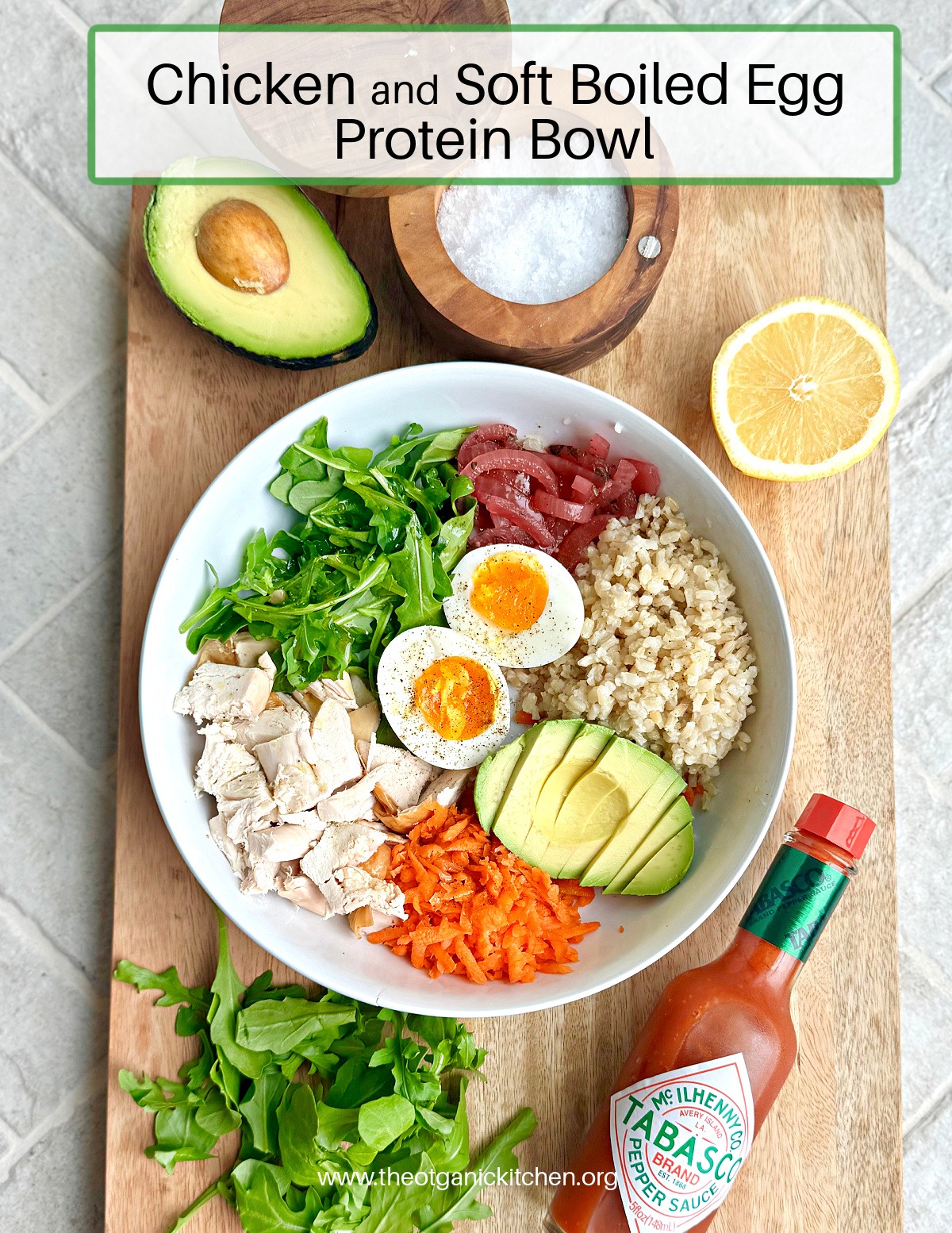 The Chicken and Soft Boiled Egg Protein Bowl! on a wood cutting board with lemon and avocado halves