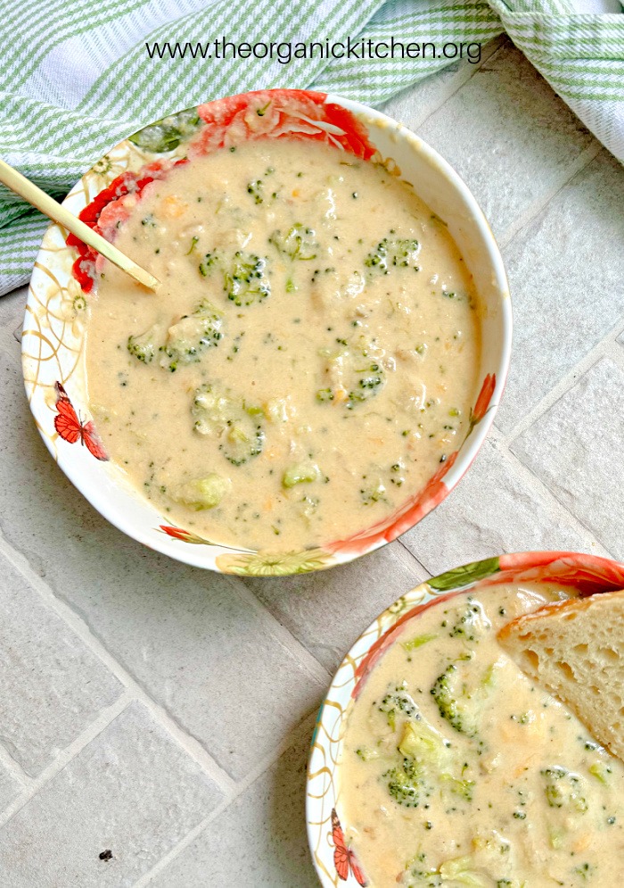  Two bowls of Easy Broccoli Cheddar Soup on brick surface with dish towel in background
