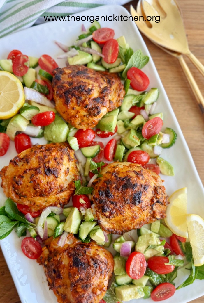 Mediterranean Chicken with Chopped Salad (Whole30) on white plate, with gold spoons to the right and a green and white dish towel above