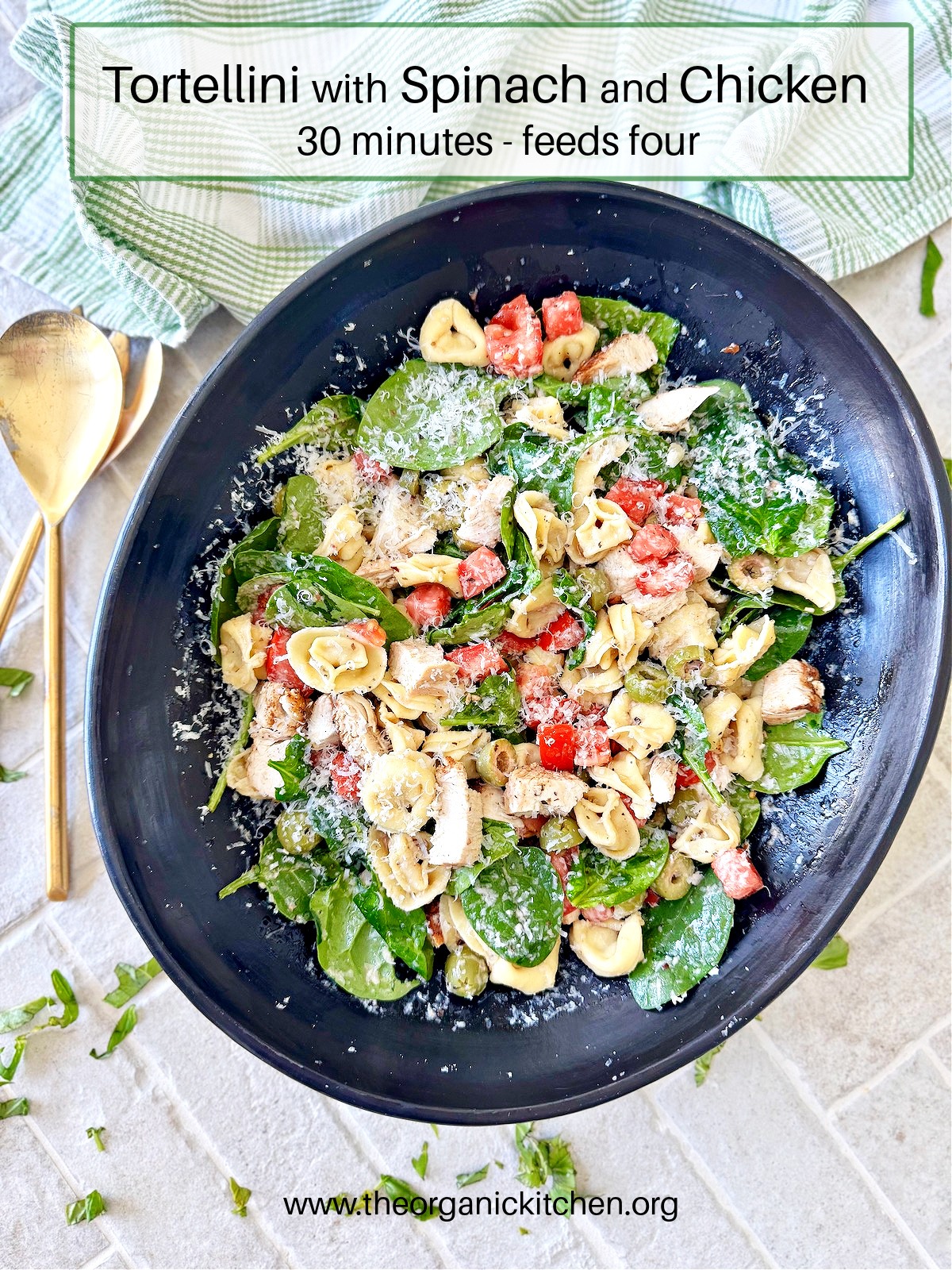 Tortellini with Spinach and Chicken in black bowl with gold utincils and green and white dish cloth in the background