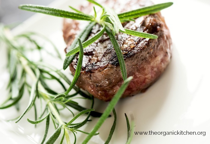 Perfect Filet Mignon garnished with rosemary on white plate
