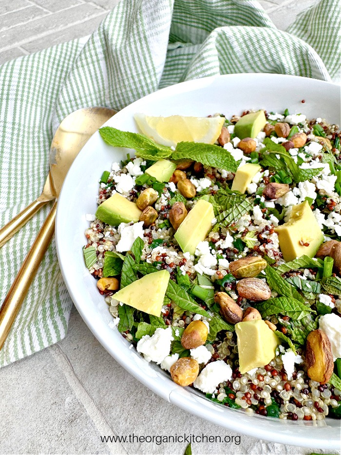 Quinoa Avocado Salad in hite bowl garnished with lemon wedge and mint leaves