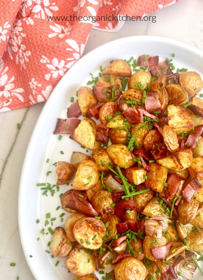 Air Fryer Potatoes with Bacon (Whole30) garnished with herbs on white plate set on marble surface