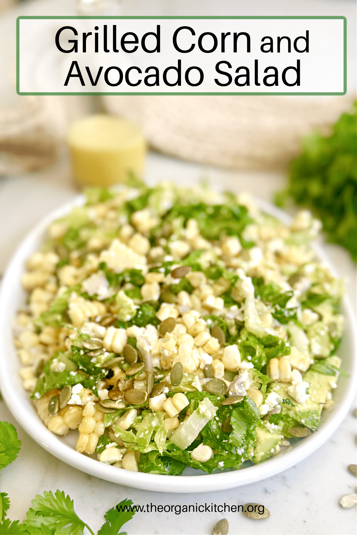 Grilled Corn and Avocado Salad on white plate with cilantro and a bottle of salad dressing in the background