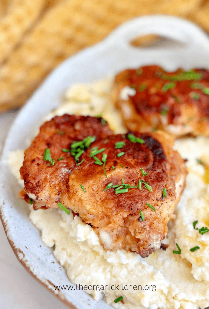 Crispy Fried Chicken Thighs  Crispy Fried Chicken Thighs garnished with chives on a bed of cauliflower puree in a bowl