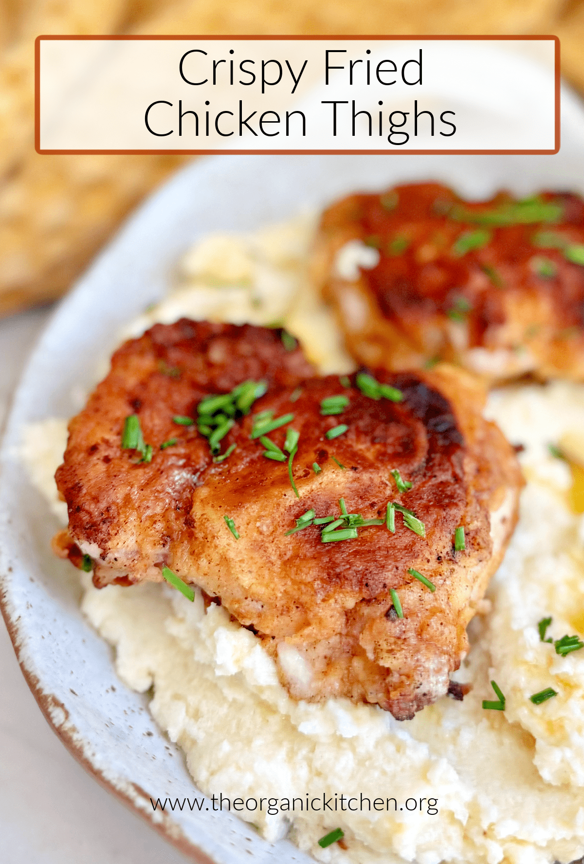 Crispy Fried Chicken Thighs  Crispy Fried Chicken Thighs garnished with chives on cauliflower mash with yellow dish towel in background