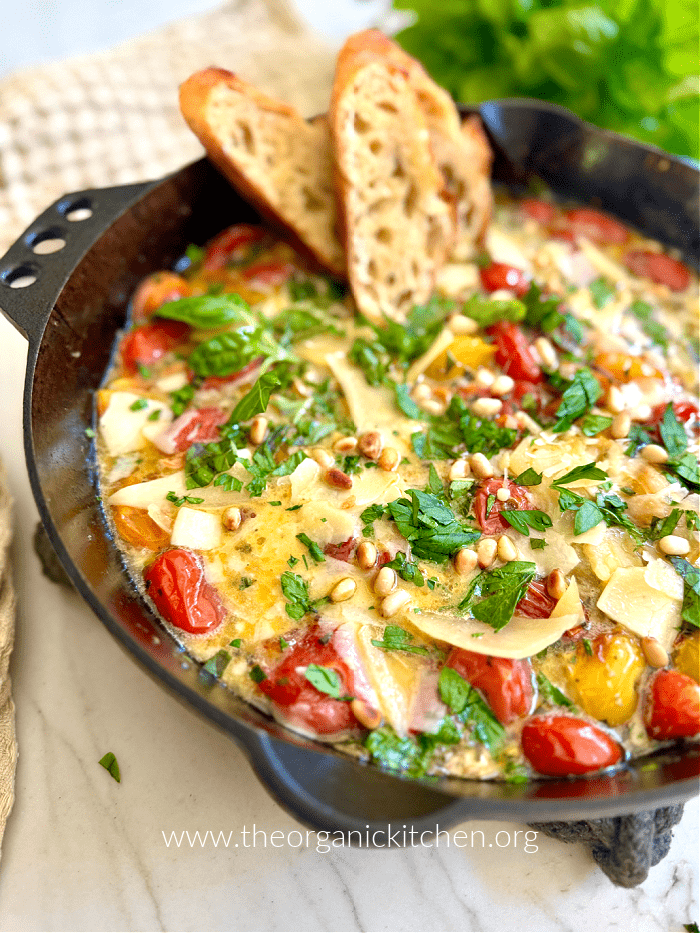 A black cast iron pan filled with tomato burrata dip and two bread slices
