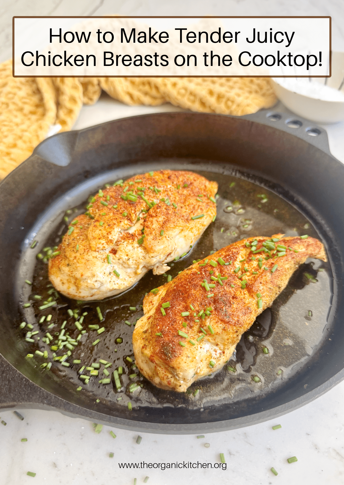 How to Make Juicy Chicken Breasts on the Cooktop A black cast iron pan with two juicy chicken breasts in it, garnished with chives