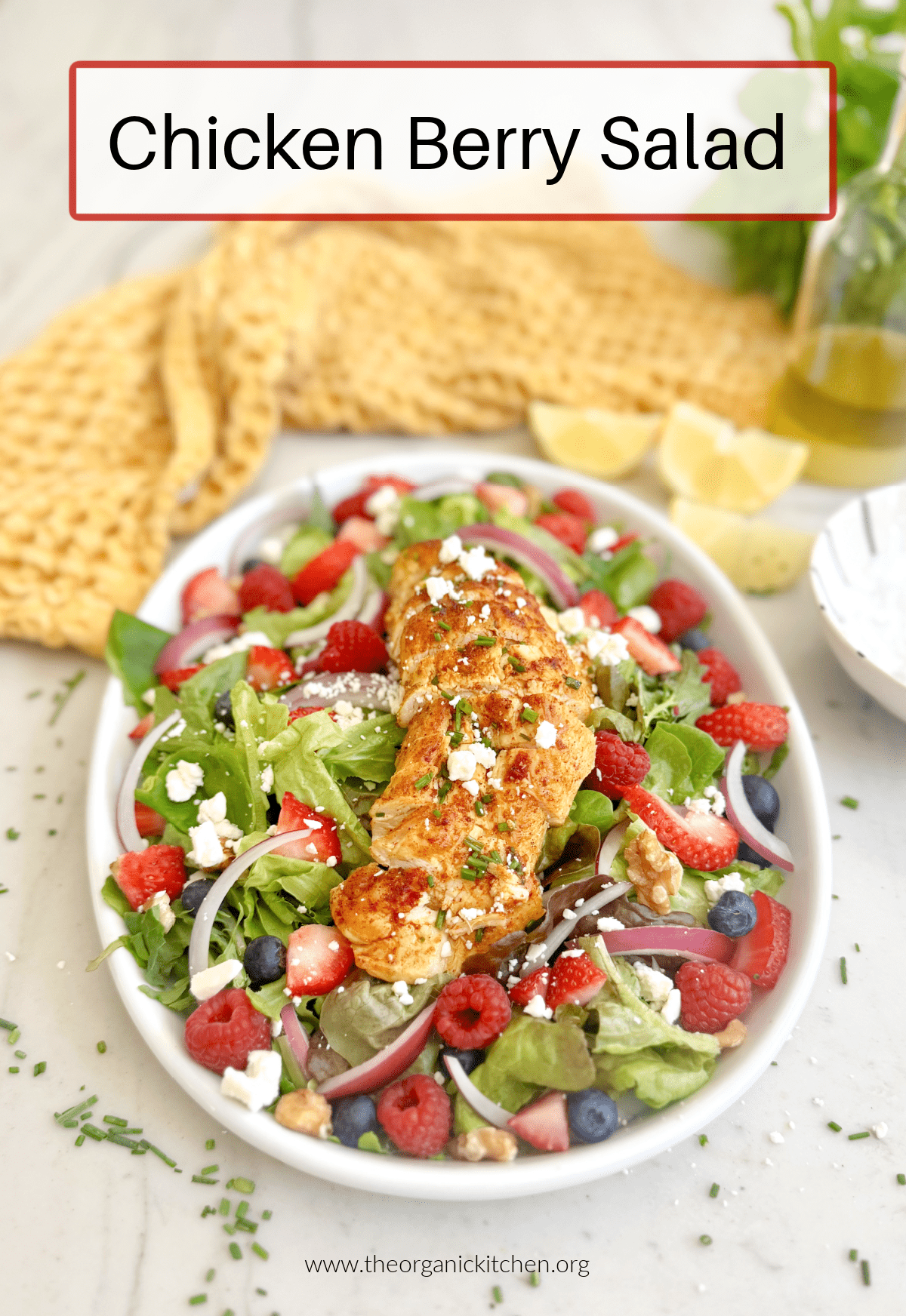 Chicken and Berry Salad: a white plate with greens, berries and chicken breast with yellow dish towel in background
