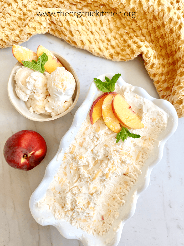 Fresh Peach "No Churn" Ice Cream garnished with peach slices and mint in white dishes with yello dish towel above