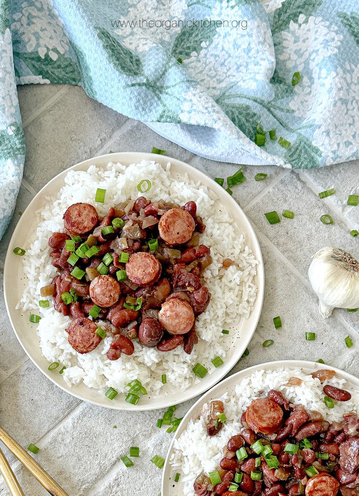 Crock Pot Red Beans and Rice Two plates of Crock Pot Red Beans and Rice garnished with green onions with blue and white dish towel in background