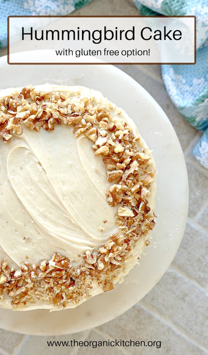 Hummingbird Cake topped with walnuts on a white cake plate