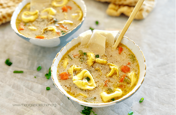 20 Minute Creamy Tortellini Soup garnished with herbs in two bowls on marble counter