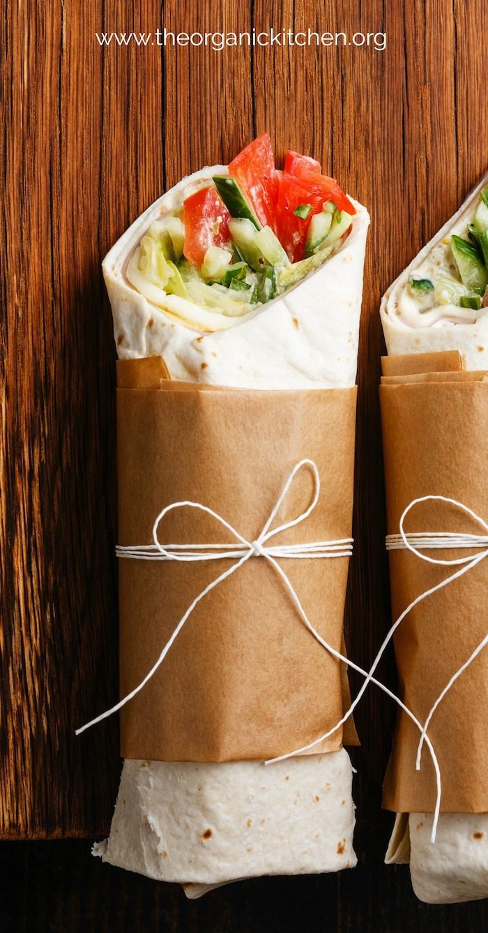 A vegetable wrap tied with string on wood table as part of a collection of Six Easy, Healthy Lunch Wraps