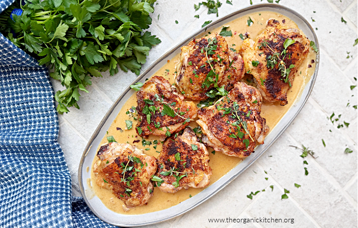 Chicken in Cream Sauce Chicken in Cream Sauce garnished with parsley on grey plate with herbs amd dish towel to the side