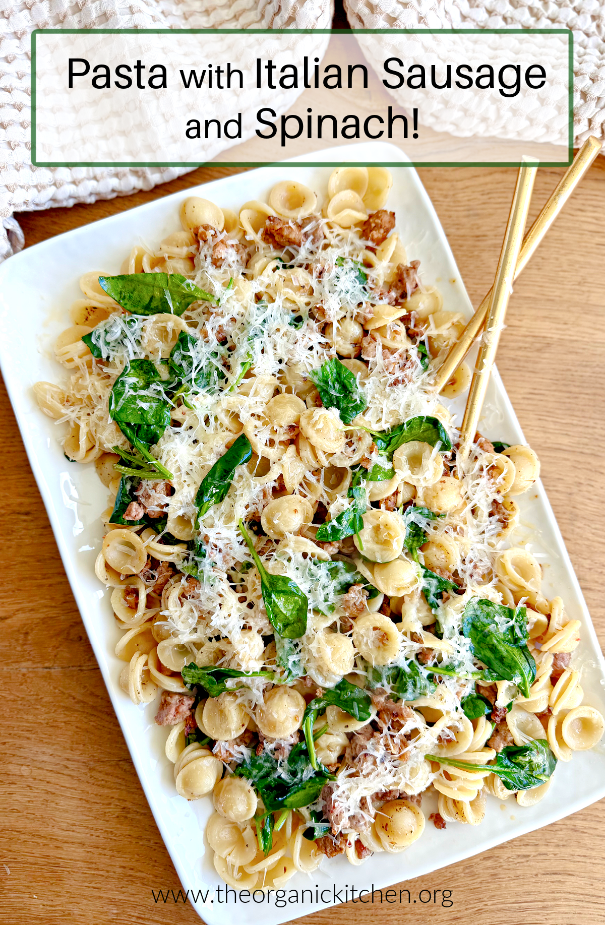 Pasta with Italian Sausage and Spinach Pasta with Italian Sausage and Spinach garnished with Parmesan on white platter set on wood table