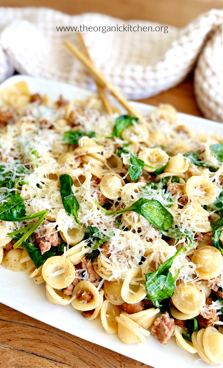 Pasta with Italian Sausage and Spinach Pasta with Italian Sausage and Spinach garnished with parmesan cheese with beige and white dish towel in background