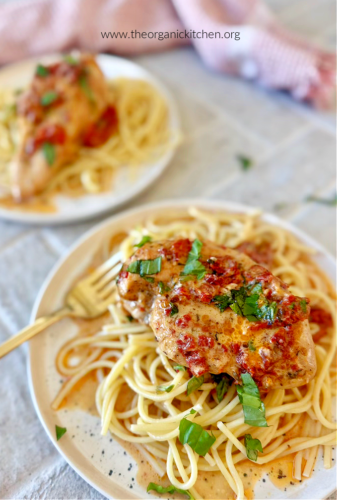 Marry Me Chicken garnished with parsley on top of pasta on white plates