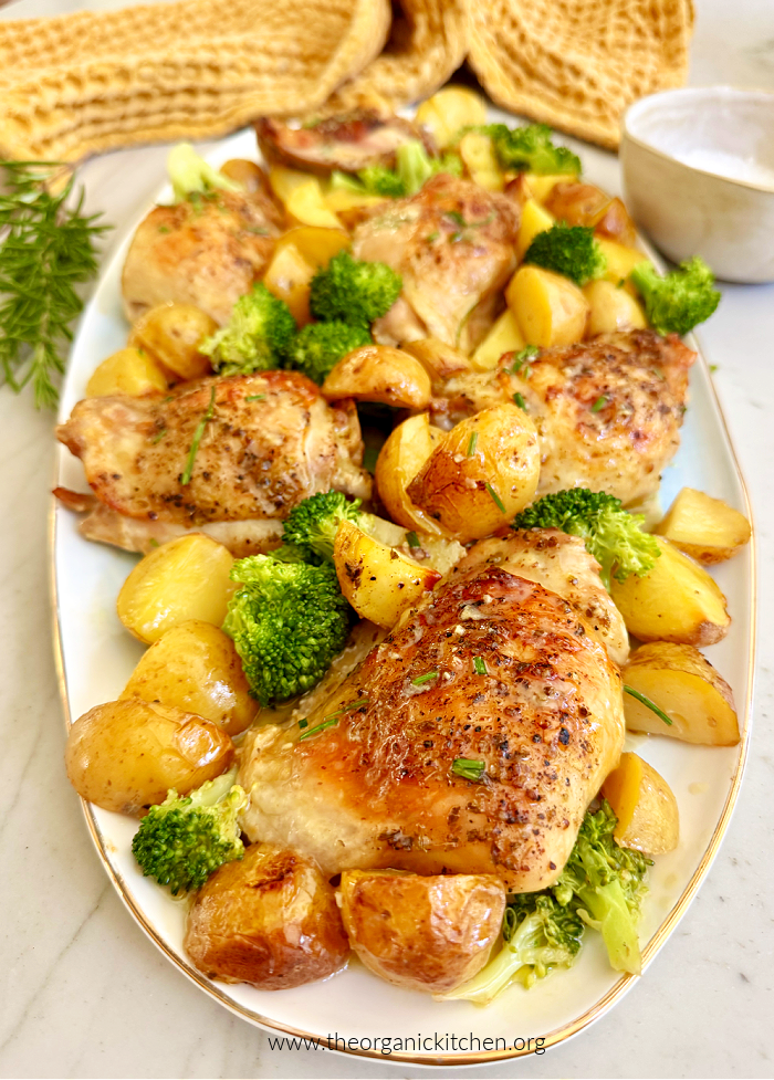 Lemon Chicken and Potatoes with broccoli on white plate with yellow dish towel in the background. 15 Healthy Chicken Thigh Recipes