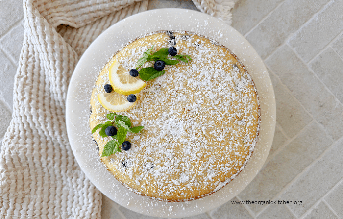 Lemon Blueberry Olive Oil Cake Lemon Blueberry Olive Oil Cake sprinkled with powdered sugar and garnished with blueberries and lemon wedges on white cake plate