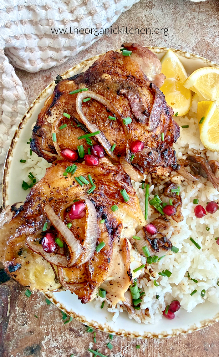 Buttery Lemon Thyme Chicken Thighs garnished with herbs and pomegranate seeds on weathered wood cutting board. 15 Healthy Chicken Thigh Recipes