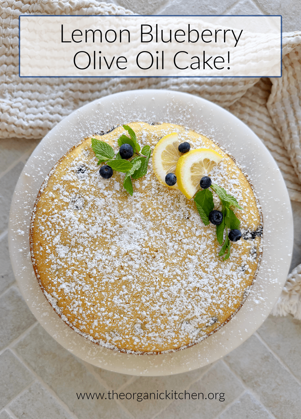 Lemon Blueberry Olive Oil Cake Lemon Blueberry Olive Oil Cake sprinkled with powdered sugar and garnished with blueberries and lemon wedges on white cake plate