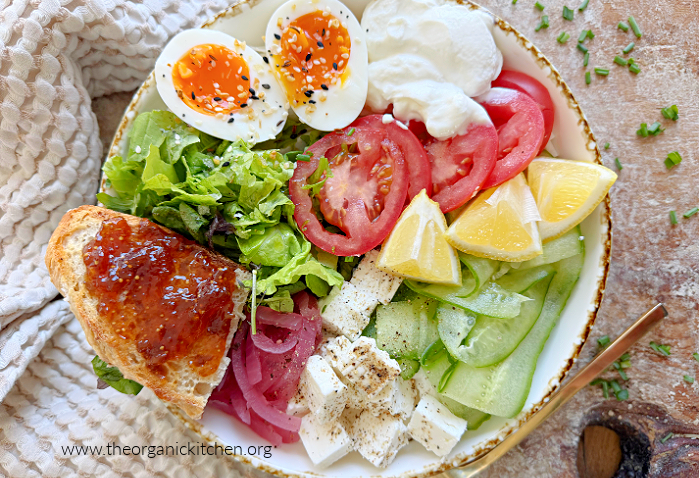 Healthy Mediterranean Breakfast Healthy Mediterranean Breakfast: greens, soft boiled eggs, cucumber, tomatoes, greens and a piece of toast in a bowl