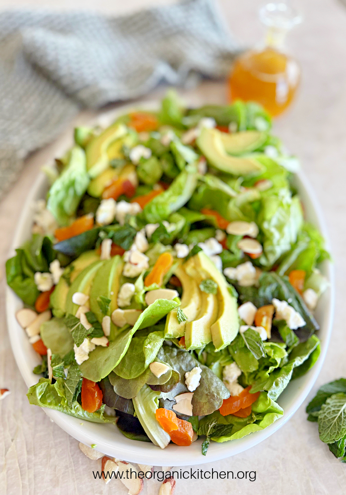20 Easy Summer Side Dishes California Summer Salad with feta and avocados on white plate with bottle of dressing and dish towel in the background