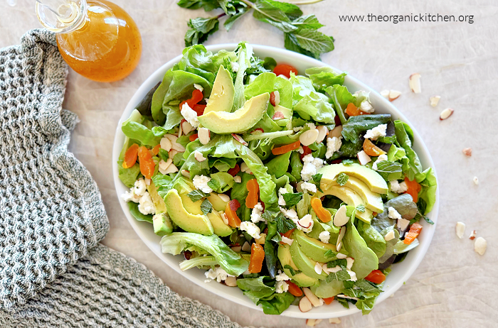 California Avocado Salad with Orange Vinaigrette California Avocado Salad with Orange Vinaigrette on white plate with orange vinaigrette in a bottle and green dish towel on the side