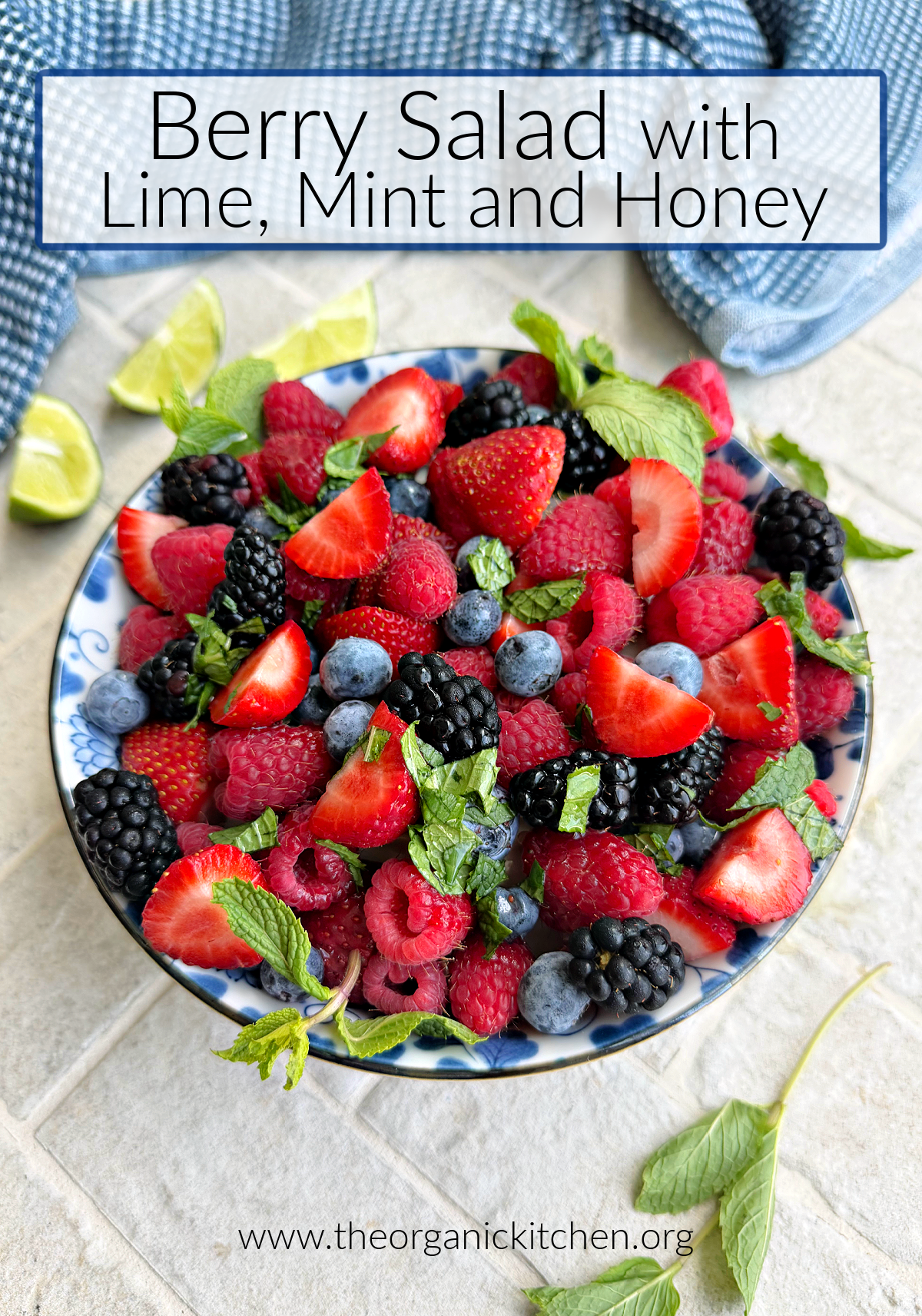 Summer Berries with Lime, Mint and Honey in blue and white bowl surrounded by mint, lime wedges, and blue dish towel