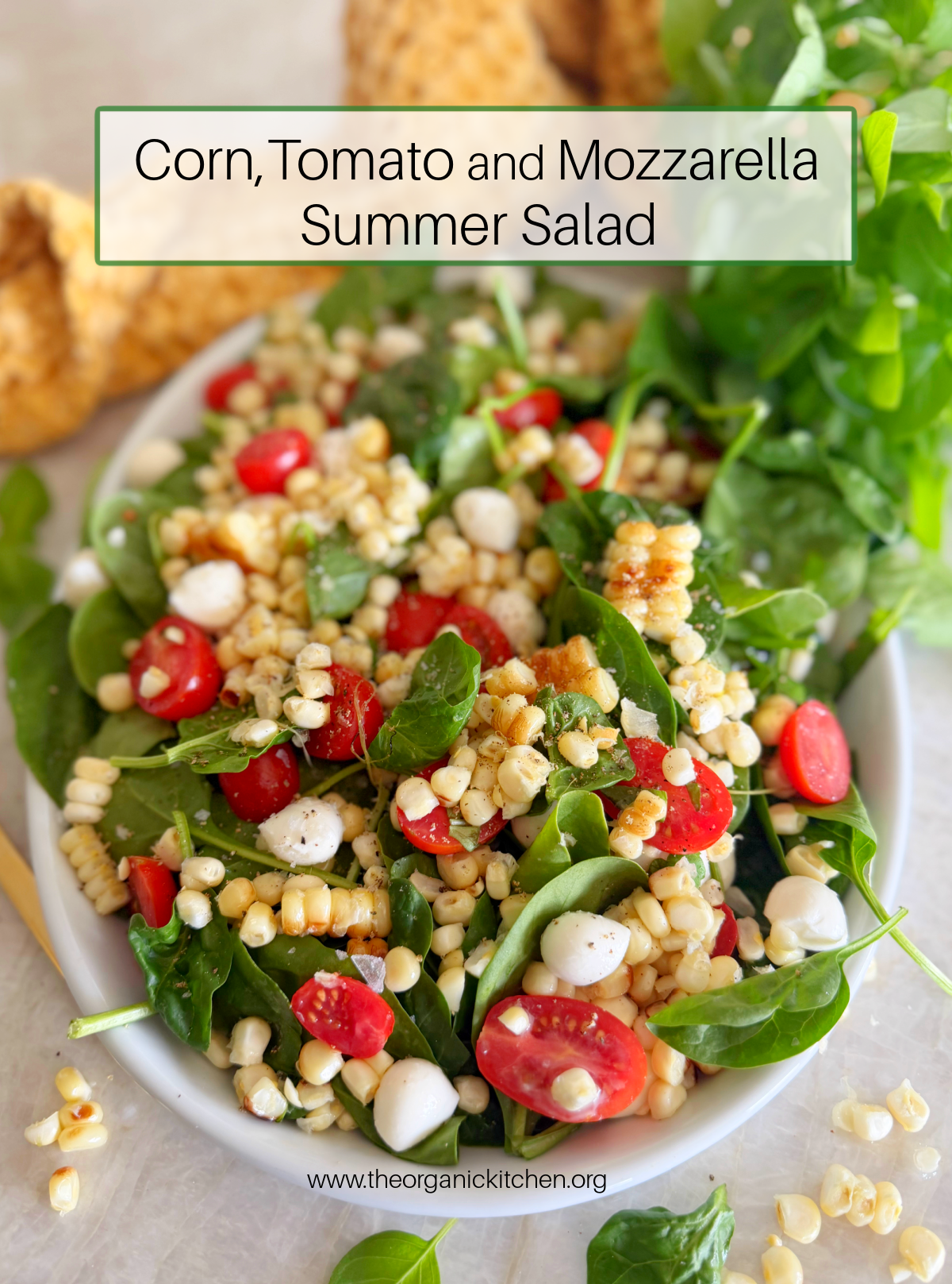 Corn, Tomato and Mozzarella Salad A white platter filled with spinach, corn, tomatoes and mozzarella with basil and a yellow dish towel in the background