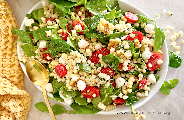 Corn, Tomato and Mozzarella Salad Corn, Tomato and Mozzarella Salad on a white plate with a gold spoon