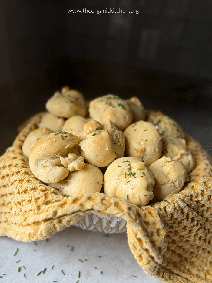 Parker House Rolls brushed with butter and garnished with chives in bowl