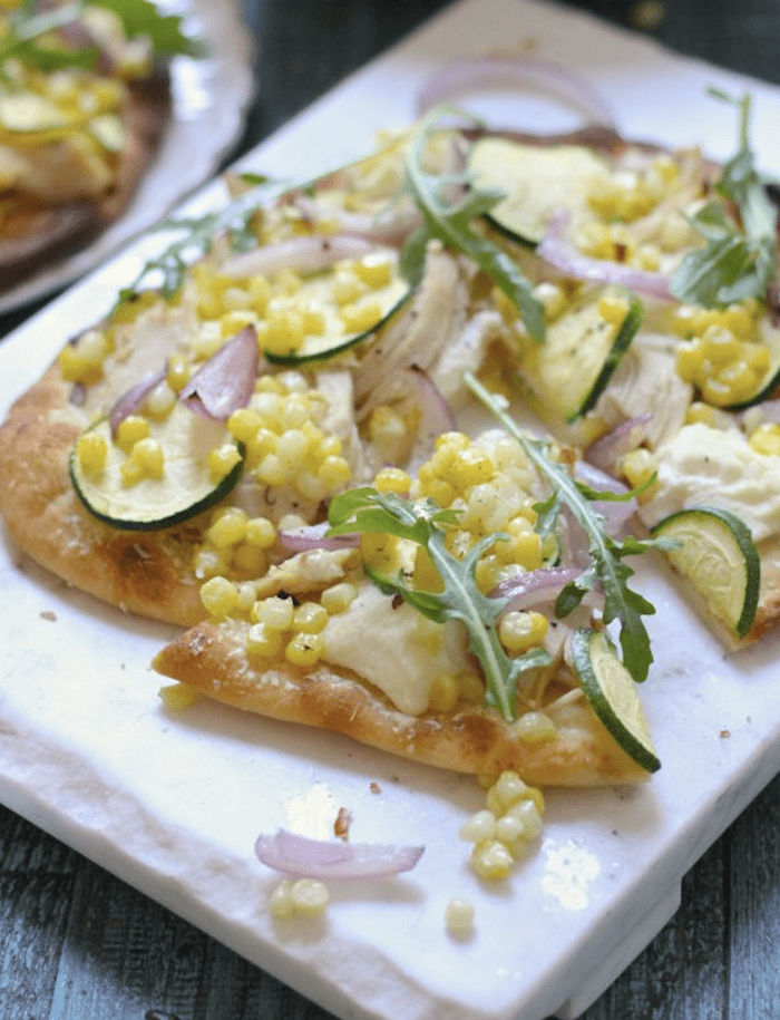 Eight Summer Corn Recipes Grilled Naan Pizza with Zucchini and Corn on a white platter
