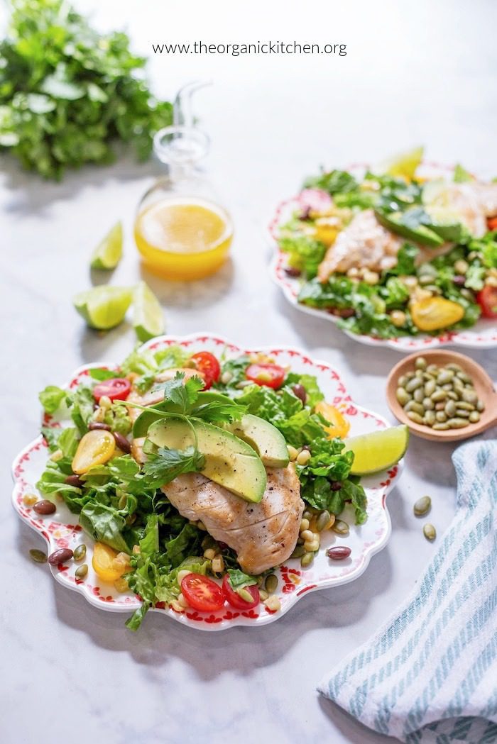 15 Recipes Using Cherry Tomatoes Southwest Chicken Salad with tomatoes, avocado and lime wedges on two colorful plates with herbs and a bottle of dressing in the background
