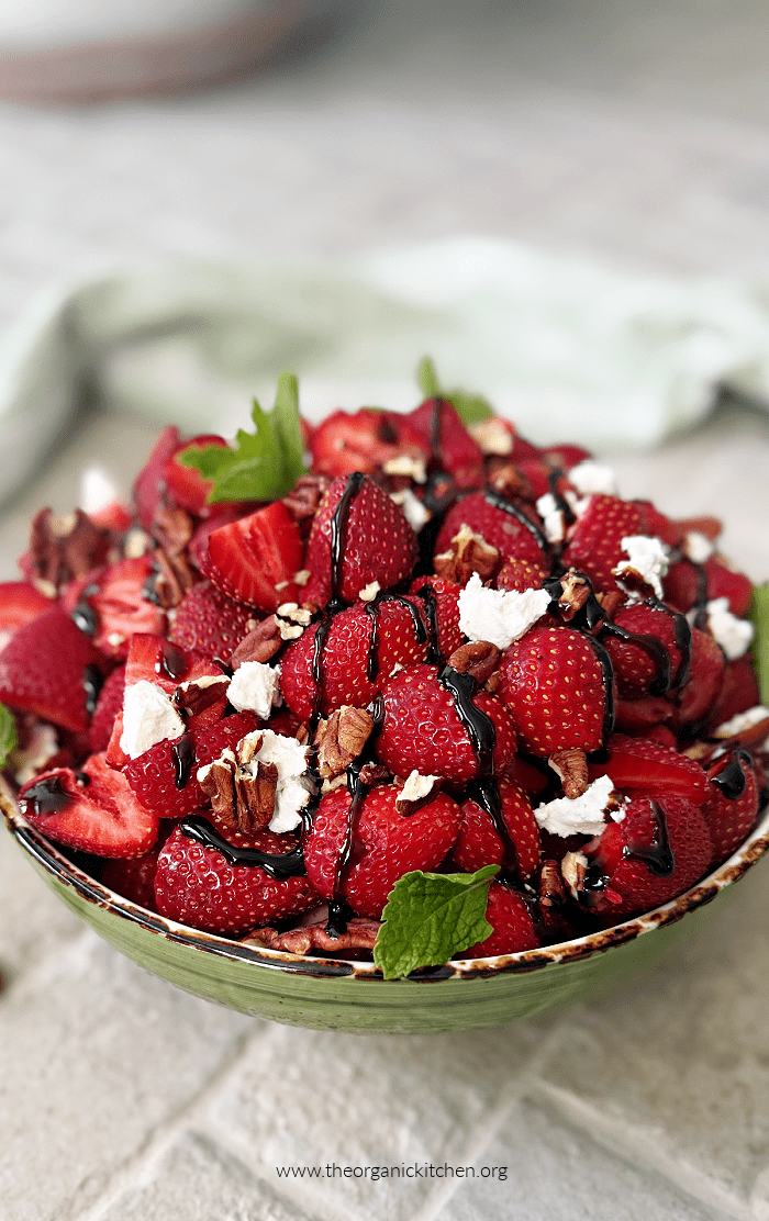 Easy Strawberry Goat Cheese Salad Easy Strawberry Goat Cheese Salad garnished with mint, in a green bowl on brick surface