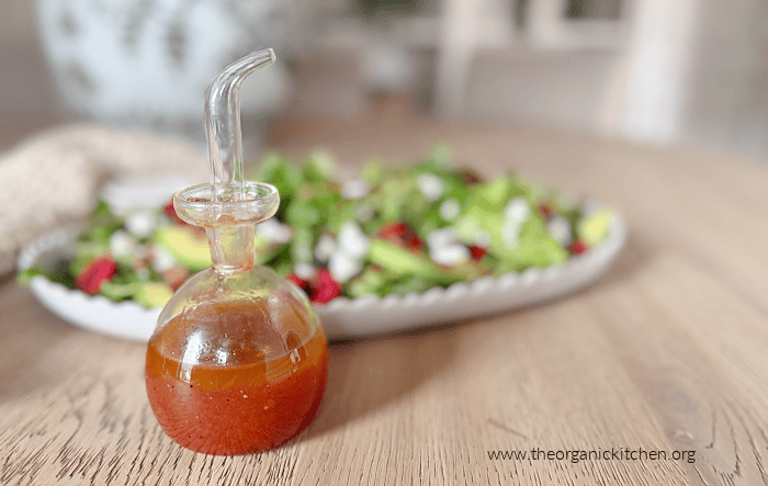 Homemade Cherry Vinaigrette Homemade Cherry Vinaigrette dressing in a small bottle with a salad on a white plate in the background