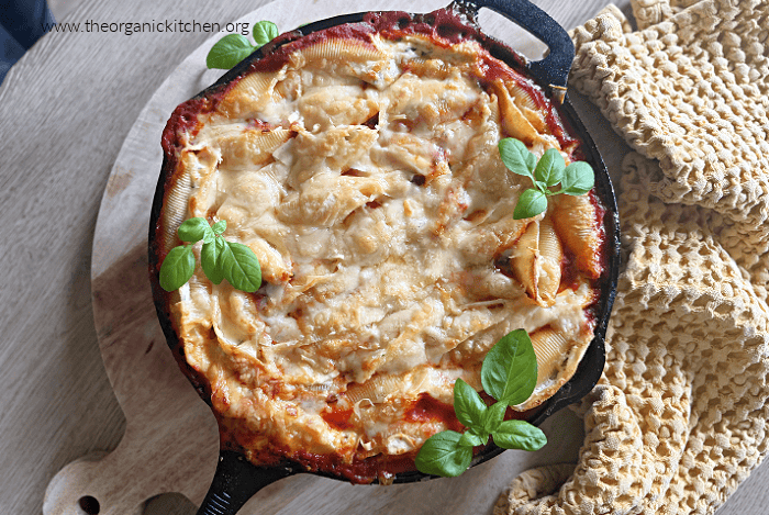 Three Cheese Stuffed Shells Three Cheese Stuffed Shells with lots of melted cheese in a black cast iron pan on wood cutting board