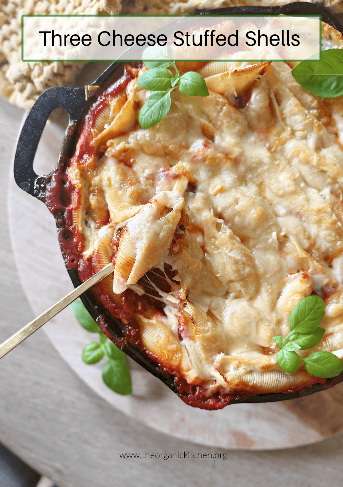 Three Cheese Stuffed Shells Three Cheese Stuffed Shells garnished with basil in a cast iron skillet with a gold spoon