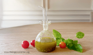 Basil Vinaigrette in a small glass bottle with cherry tomatoes and basil leaves in the background