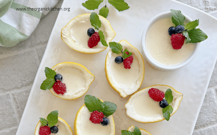 Easy Lemon Posset Easy Lemon Posset- a white tray with lemon halves and ramekins filled with lemon custard garnished with mint and berries with green and white dish towel in the background