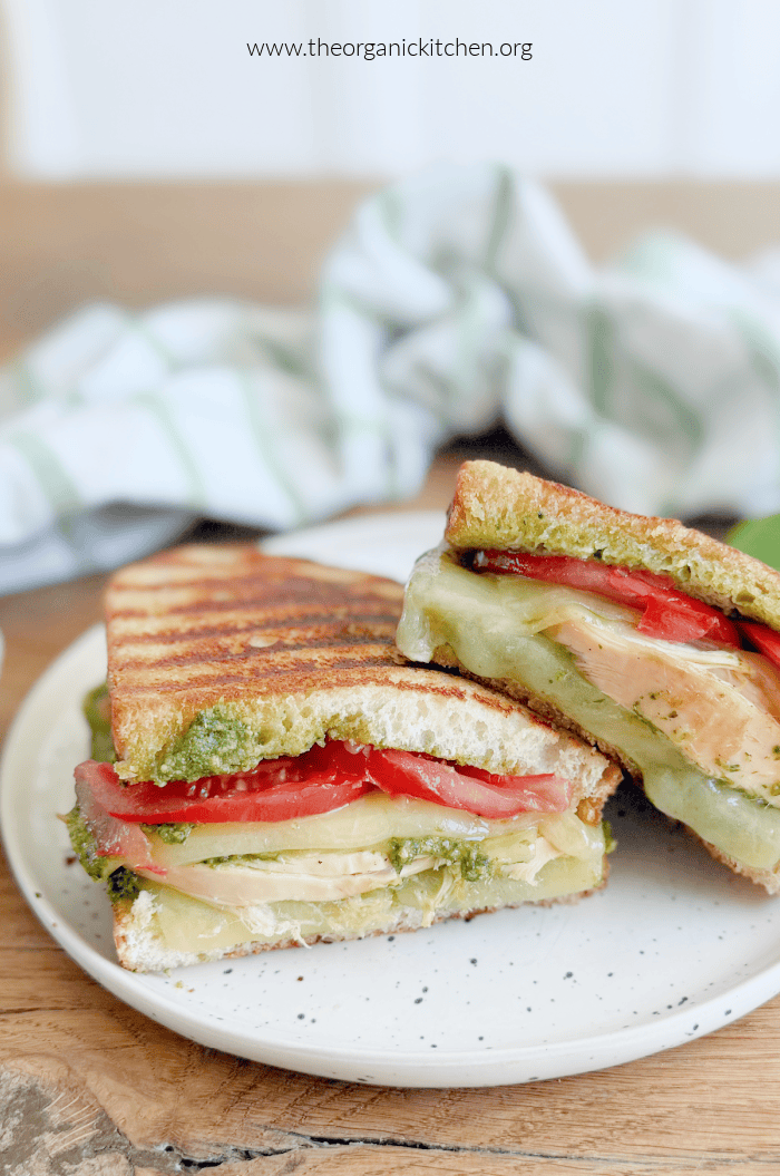 Chicken Pesto Grilled Cheese Sandwich on white plate with green and white dish towel in the background