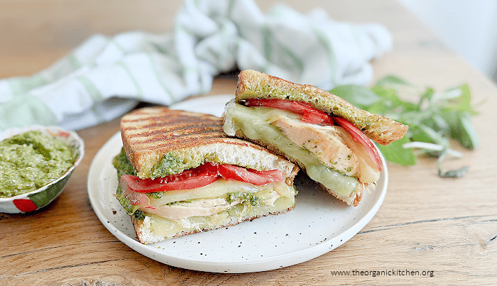 Chicken Pesto Grilled Cheese sandwich on a white plate with a small dish of pesto on the side