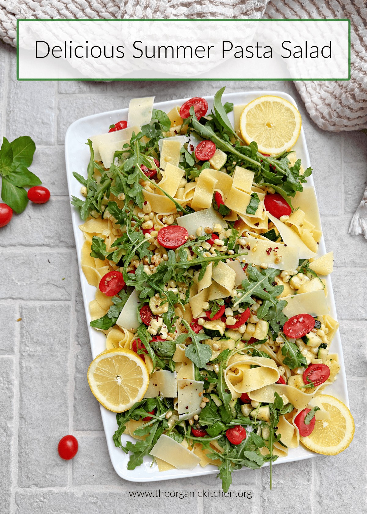 Delicious Summer Pasta Salad with tomatoes, arugula and lemon slices on white platter