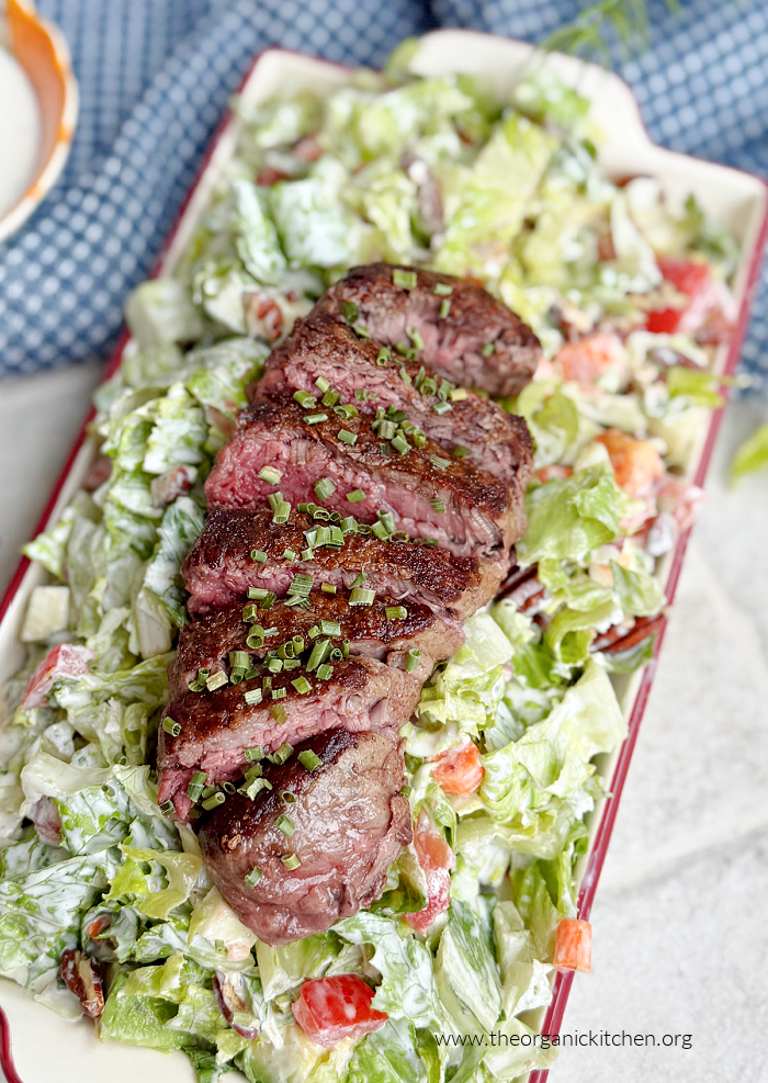 Filet Mignon with Chopped Salad on white plate with blue dish towel in the background