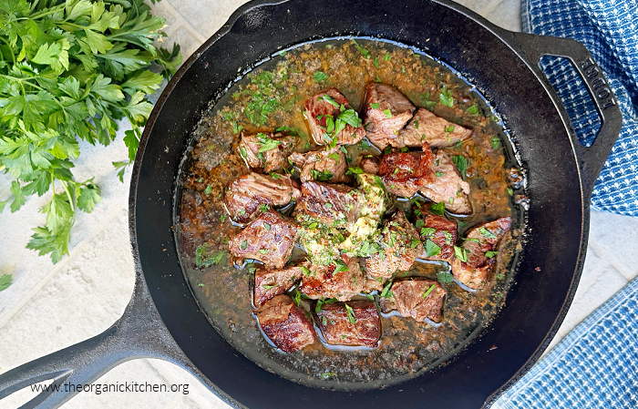 Cowboy Butter Steak Bites Cowboy Butter Steak Bites in a black cast iron pan with herbs and dish towel in the background